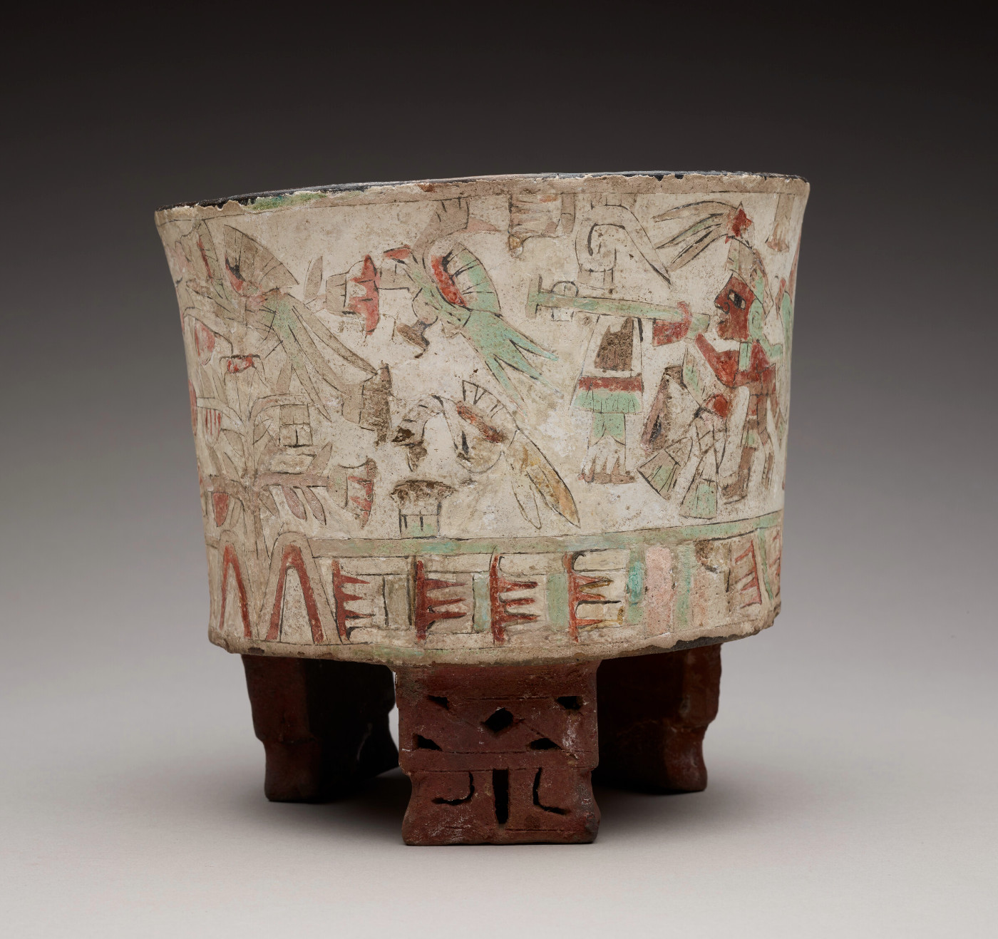 A tripod ceramic vessel with decorative feet and figures painted on the exterior.